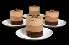 A photo of 4 Chocolate Mousse Cakes on small, white dessert dishes.